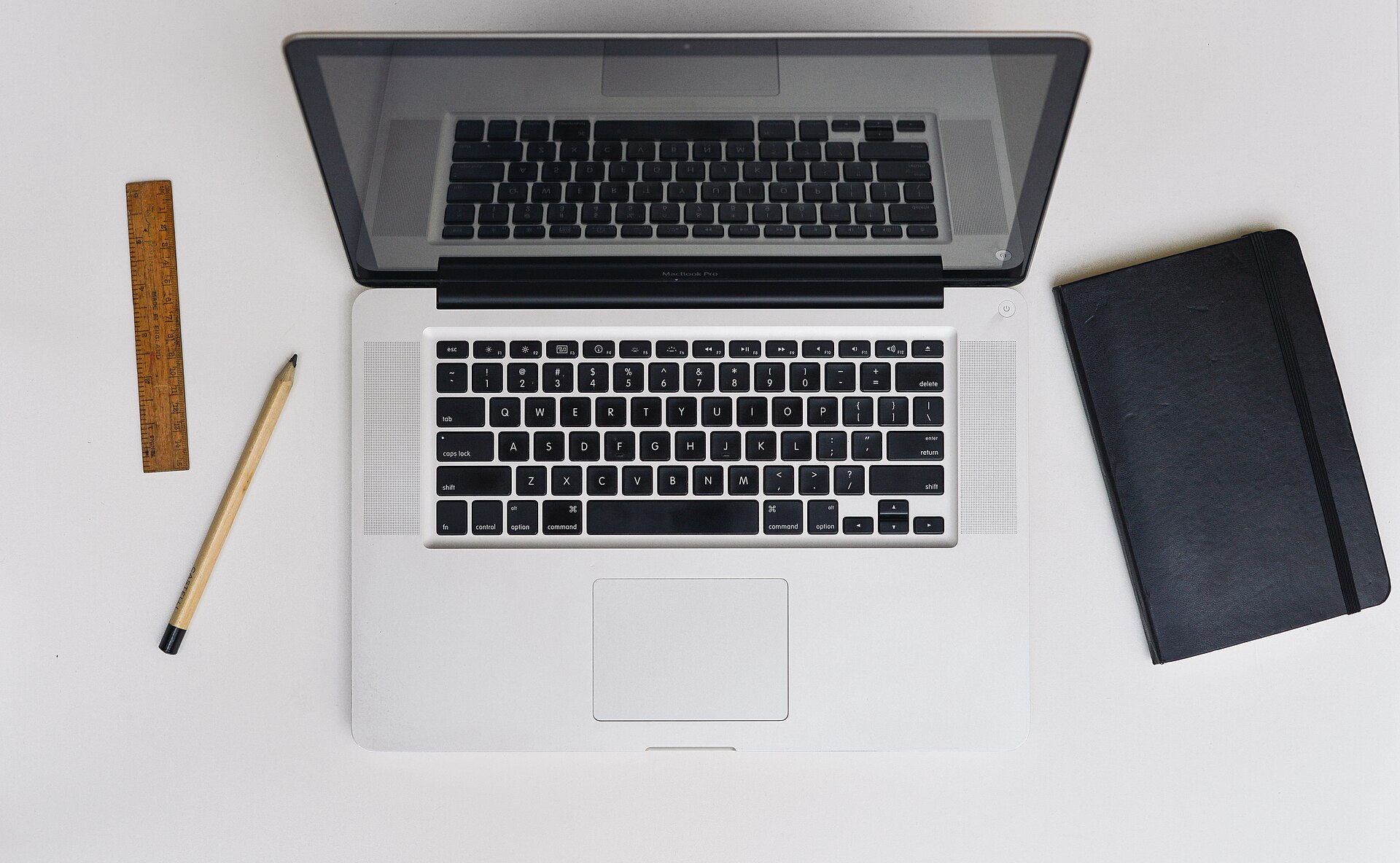 Laptop on a clean desk Open laptop on a white desk with a notebook, pencil and ruler beside it